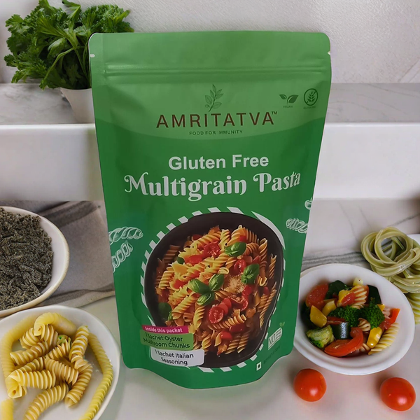 Amritatva gluten-free multigrain pasta package on a table with pasta and ingredients.